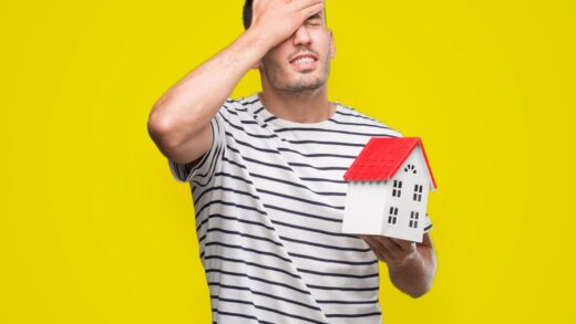 Przystojny agent nieruchomości trzymający dom zestresowany z ręką na głowie, zszokowany ze wstydem i zaskoczeniem na twarzy, zły i sfrustrowany. Strach i zdenerwowanie z powodu błędu.
