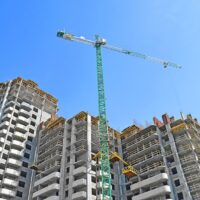 Żuraw budowlany i budynek w budowie na tle błękitnego nieba