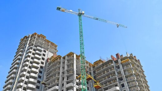 Żuraw budowlany i budynek w budowie na tle błękitnego nieba